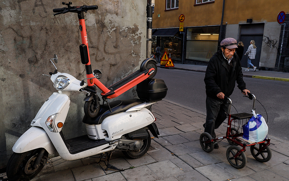 Felparkerad elscooter &auml;ldre man med rullator