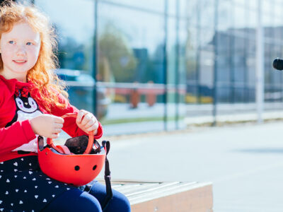 flicka som sitter p&aring; b&auml;nk med cykelhj&auml;lm i handen