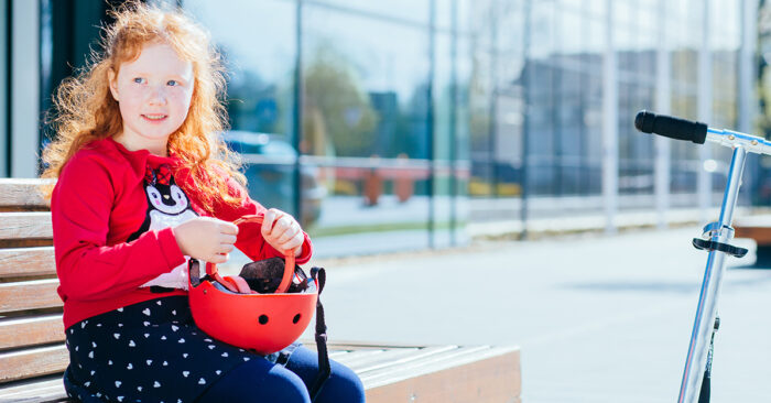 flicka som sitter p&aring; b&auml;nk med cykelhj&auml;lm i handen